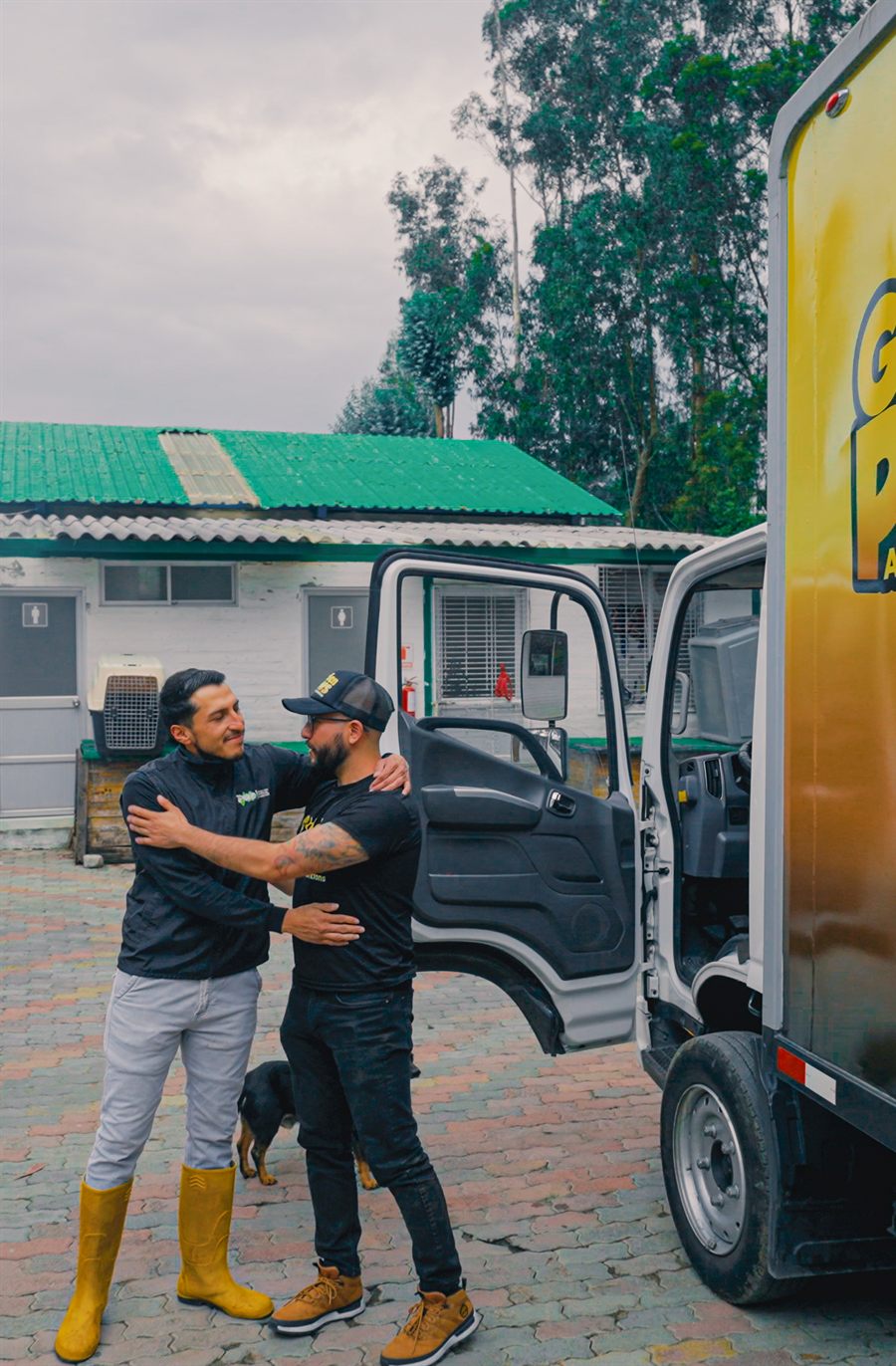 Dos integrantes del equipo de Golden Paws se abrazan junto al camión de una entrega de alimento.