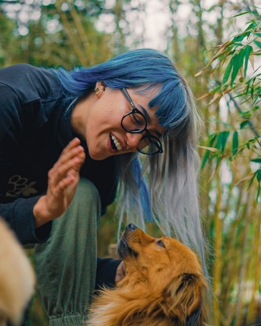Una integrante del equipo sonríe mientras un perrito la mira.